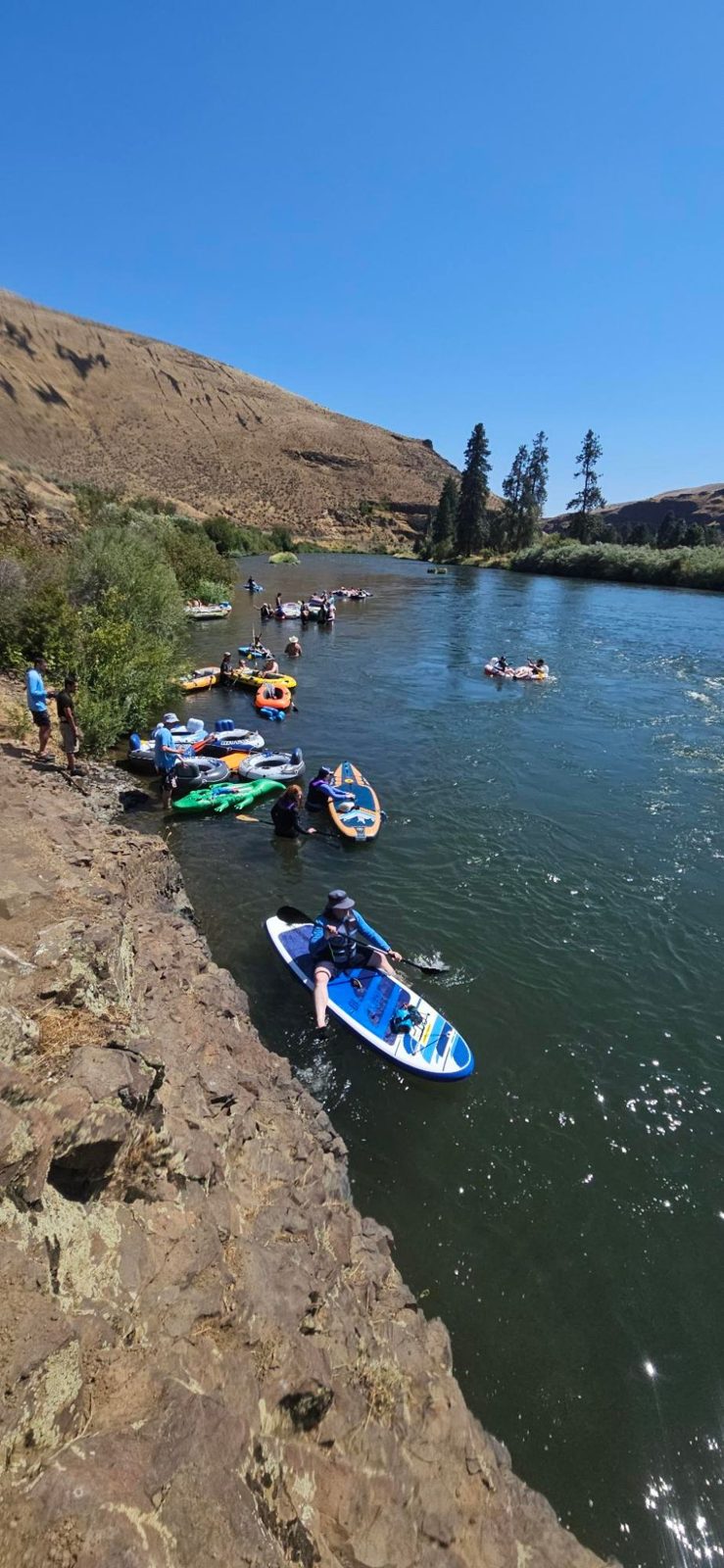 Tubes, kayaks and boards staging on the bank below the rock